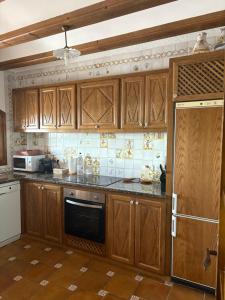 a kitchen with wooden cabinets and a stove top oven at Cal Nicet in Perafita