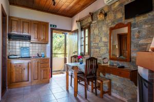a kitchen with a table and chairs and a stone wall at Maistros Studios in Damouchari +49 photos