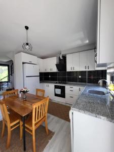 a kitchen with white cabinets and a wooden table at Duplex Villa with Private Pool in Akyaka Ataköy in Muğla