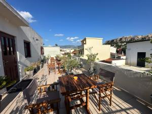 a balcony with wooden tables and chairs on a building at Theasis Athens in Athens