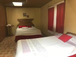 a bedroom with two beds and a window with red curtains at Lagunillas Del Poas in Poasito