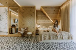 a girl sitting on a bed in a hotel room at Willa Regina I Resort & SPA in Zakopane