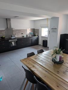 a large kitchen with a wooden table and chairs at Gite a la ferme in Courcelles-les-Lens