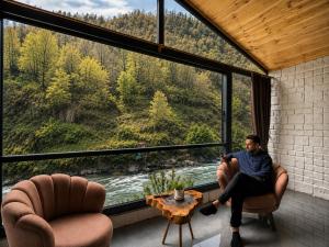 a man sitting in chairs in a room with a large window at Villa Del Rio Karadeniz River Palace Ayder in Çamlıhemşin