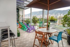 a balcony with chairs and a table and an umbrella at Hotel Sixtina Plaza Medellin in Medellín
