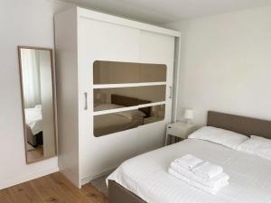 a white bedroom with a bed and a mirror at Marc Apartament in Turda