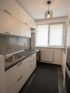 a kitchen with white cabinets and a sink at Marc Apartament in Turda +2 photos