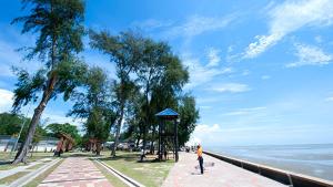 a person standing on a sidewalk near the water at Shareen Homestay Morib in Banting