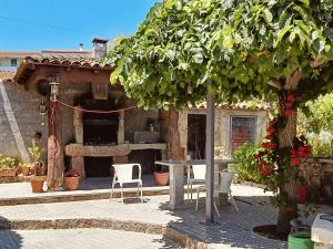 a patio with a table and chairs under a tree at Casajurada in Pinhel