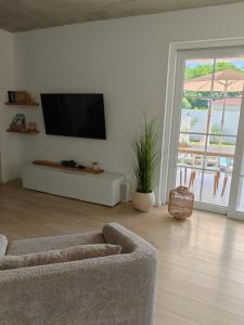 a living room with a couch and a television on a wall at Villa Sunrise Labin Istria - a smile every day in Nedeščina