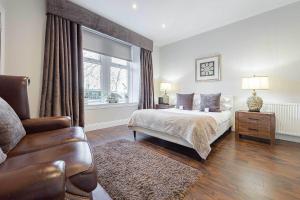a bedroom with a bed and a chair and a window at Falkirk Apartments Queen Street in Falkirk