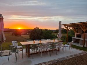 a table and chairs with the sunset in the background at Gîte familial 10 pers jardin et piscine in Saint-Amour