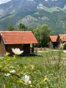 a cabin with a red roof with mountains in the background at ABBA Ethno House in Gusinje