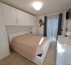 a white bedroom with a bed and a window at Villetta Col Ranzola in Brusson