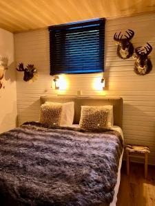 a bedroom with a bed with antlers on the wall at Cabane La Folie Douce in Hotton