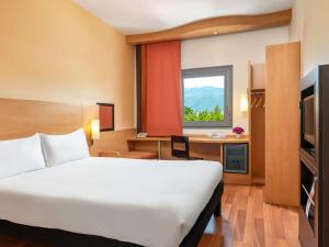 a hotel room with a bed and a desk and a window at Ibis Bursa in Bursa