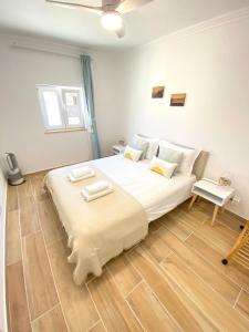 a bedroom with a large white bed and a wooden floor at Casa do Sol in Sagres