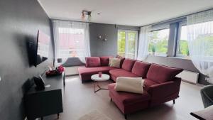 a living room with a red couch and windows at Apartment Am Paradies in Bad Lauterberg
