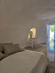 a white bedroom with a bed and a table at Porto Castello in Fira +199 photos