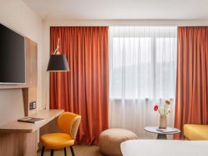 a room with a desk and a window with orange curtains at Novotel Lyon Centre-Confluence Bord de Saone in Lyon