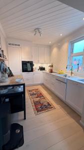 a kitchen with white cabinets and a rug on the floor at Asanzo Historic Attic-Traditional Norwegian Home & Warm Indian Hospitality in Stavanger