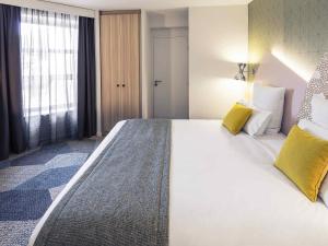 a hotel room with a large bed with yellow pillows at Hôtel Mercure Thionville Centre Porte du Luxembourg in Thionville