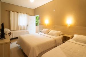 a hotel room with two beds and a television at Hotel Rio Guarujá - "Sua casa na praia" in Guarujá