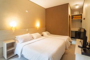 a hotel room with two beds and a television at Hotel Rio Guarujá - "Sua casa na praia" in Guarujá