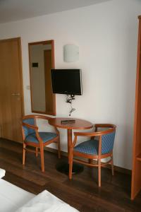 a room with a table and two chairs and a television at Hotel Tannerhof in Schenna