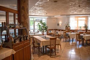 a restaurant with tables and chairs and wine bottles at Hotel Tannerhof in Schenna