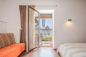 a room with a bed and a glass door with a balcony at Gerika guest house in Palanga