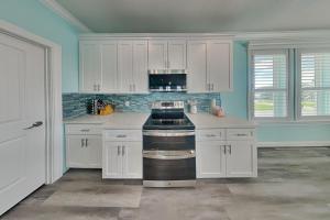 a kitchen with white cabinets and a stove top oven at Tortuga Moon in Galveston +16 photos