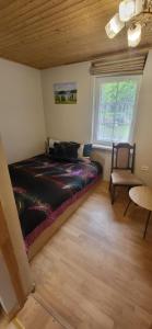 a bedroom with a bed and a chair and a window at Sodyba pas Babą - namas KLASIKA in Palanga