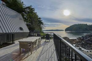 a deck with a table and chairs next to the water at Duffin Cove Resort in Tofino