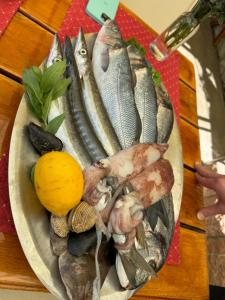 a plate of fish on a table with a lemon at Studio Sea View Steps to Przno beach w Parking Villa Olive in Pržno