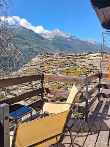 a couple of chairs sitting on a deck with mountains in the background at Casa Vanda in Châtillon