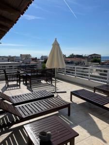 a patio with benches and an umbrella on a roof at palazzo PADINI alla costa in Neoi Epivates