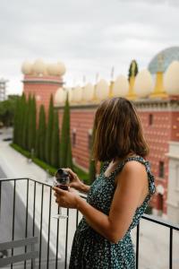 a woman standing on a balcony holding a wine glass at Apartamentos enfrente del Museo Dalí - Serena Stays in Figueres +36 photos