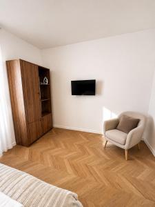a bedroom with a chair and a television on a wall at Le Thuillat Limoges in Limoges