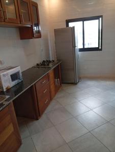 a kitchen with a refrigerator and a tile floor at Résidence Prestige KGV Appt 301 in Douala +27 photos