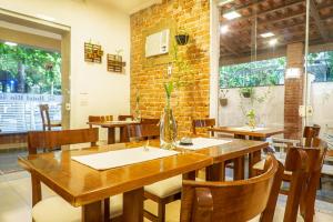 a restaurant with wooden tables and chairs and a brick wall at Hotel Rio Guarujá - "Sua casa na praia" in Guarujá +31 photos