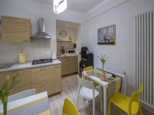 eine Küche mit einem Tisch und gelben Stühlen in einem Zimmer in der Unterkunft Affittacamere Le Quattro Stagioni in Pisa