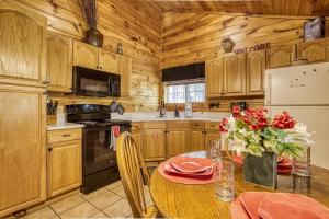 a kitchen with wooden cabinets and a table with red flowers at Mountain View Hot Tub Cabin w Pool Table Romantic in Sevierville