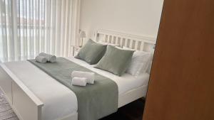 a white bed with two towels on top of it at Beach House - Aguda Beach - 2 bedrooms in Arcozelo