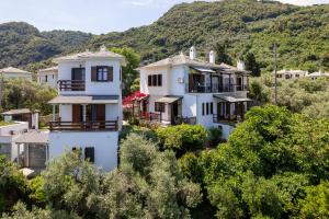 a group of white houses on a hill with trees at Maistros Studios in Damouchari