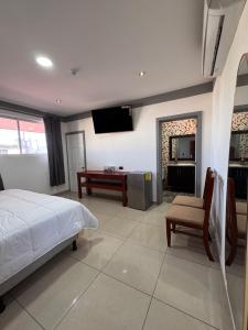 a bedroom with a bed and a desk and a television at Hotel Rubinos in San Salvador