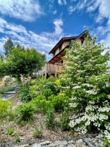 a house with a tree and flowers in front of it at Wypas Hills - domek na wyłączność in Białka Tatrzańska