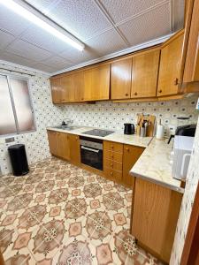 a kitchen with wooden cabinets and a tile floor at Big vacation apartment BI in Guardamar del Segura