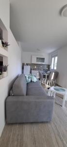 a living room with a gray couch and a kitchen at Cherry Garden Apartment in Podgorica