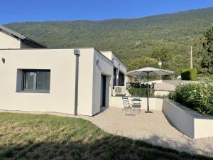 a white house with a table and an umbrella at Le Nid du Bourget in Le Bourget-du-Lac
